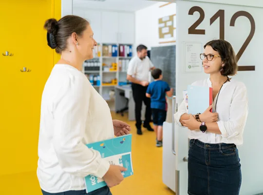 A teacher and a student stand in front of the classroom