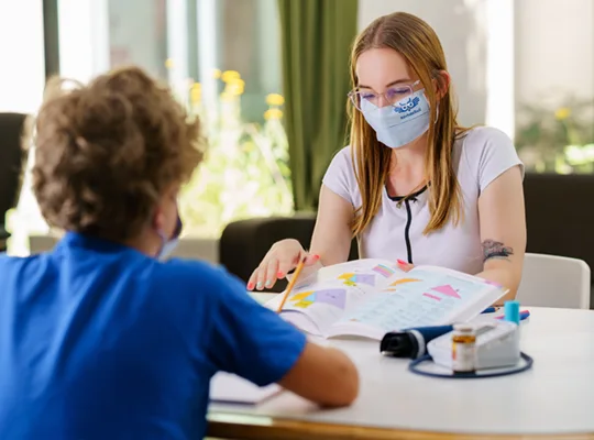 KórházSuil önkéntes tanul egy gyerekkel az asztalnál